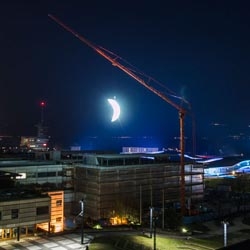 Installation in Lausanne, Switzerland, of the moon in first quarter, a waxing crescent, with the help of an industrial crane, from urban artist SpY.