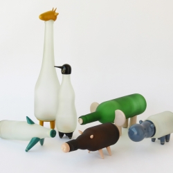 Nishi Chauhan 's Animal Farm explores the twin themes of craft revival and the repurposing of used objects. This first set of upcycled bottle lamps visualize six animal forms featuring the wood-lac turnery craft of Channapatna.