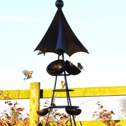 The almost 'squirrel proof' bird feeder? Metal umbrella top keeps the food bowls dry, and directs rainwater into the water bowls below; long sweeping legs make squirrel climbing difficult.