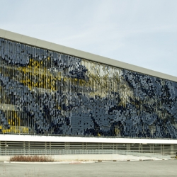 An interactive facade fronting a parking structure at the new Eskenazi Hospital in Indianapolis, Indiana.  A field of 7,000 angled metal panels in conjunction with an articulated east/west color strategy creates a dynamic façade system.
