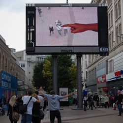 Hand from Above is an artwork for public space screens that augments a giants hand with live video to play with pedestrians.