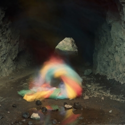 What appears to be smoke - or lighting effects - is actually the artist himself, performing with sheets of coloured paper; photographed on long-exposure...