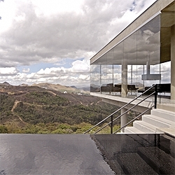 A spectacular concrete house at the top of a hill in Brazil. A beam-like volume with crystal walls offers a panoramic view of the surroundings, with a lovely endless pool. By Humberto Hermeto.