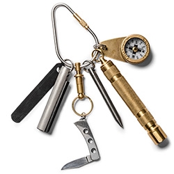 Kaufmann Mercantile's EDC Kit 2! Quick release brass key ring, stainless steel perforated folding knife, brass compass, stainless steel key chain pen, brass key chain flashlight, magnesium fire starter, and stainless steel key chain carabiner.