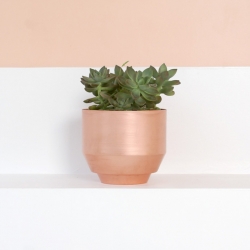 Copper planter by Yield. Incorporates a water reservoir at the base to keep standing water separate from plant.