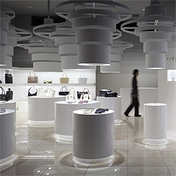 Sinato's design for Patrick Cox's shop in Tokyo. A series of pedestals lit by independent fixtures center the focus on the products, while the rest of the shop is kept almost in the dark.